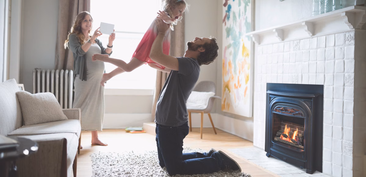 dad lifting daughter while pregnant mom takes photo