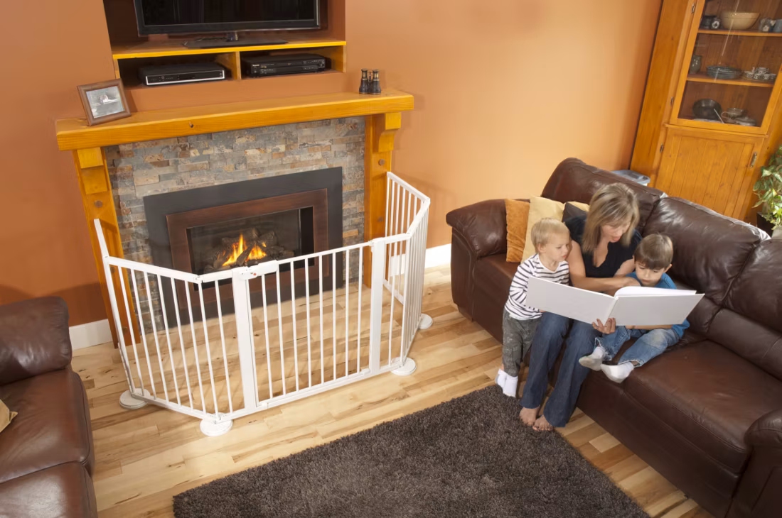 mom reading book to two kids, safety gate around fireplace
