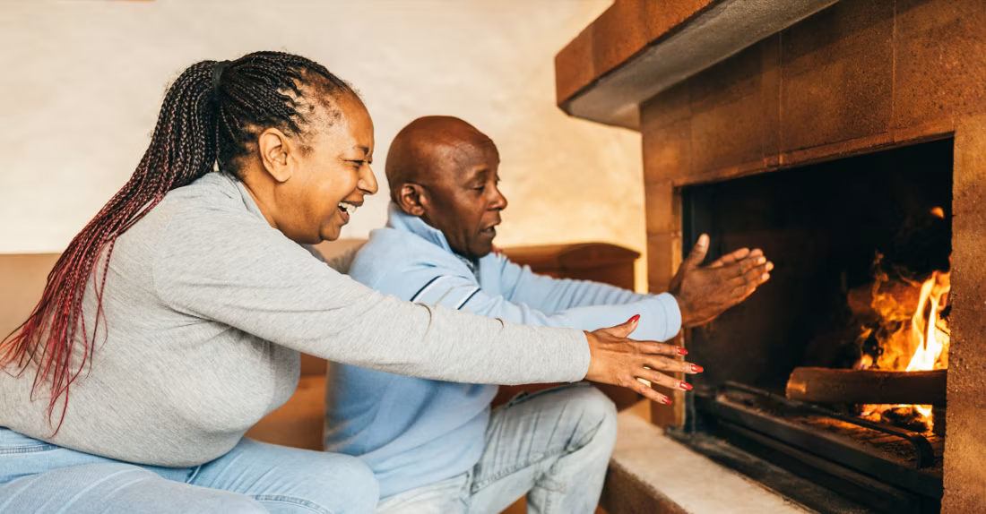 senior couple warming hands at wood fire
