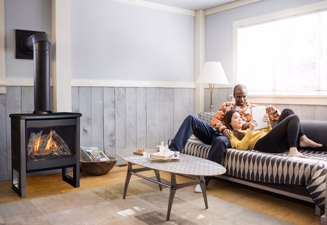 couple relaxing on sofa with tablet near freestanding stove