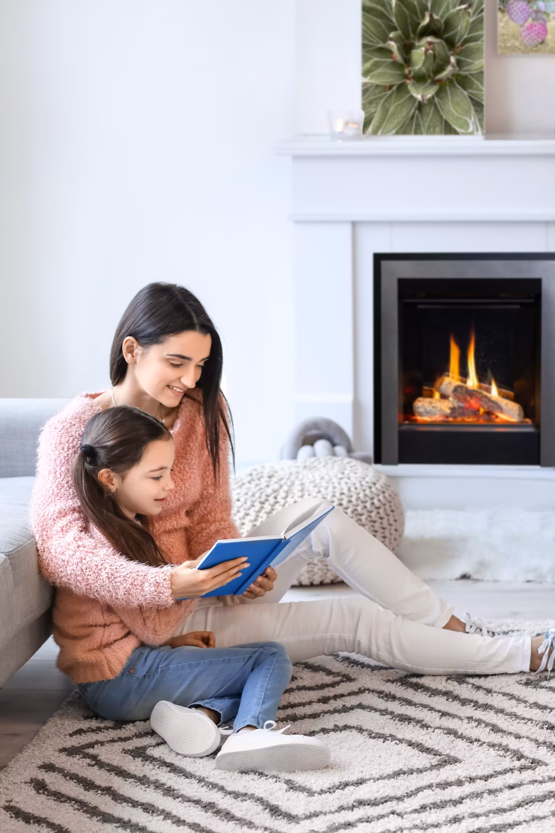 mother and daughter reading beside electric fireplace