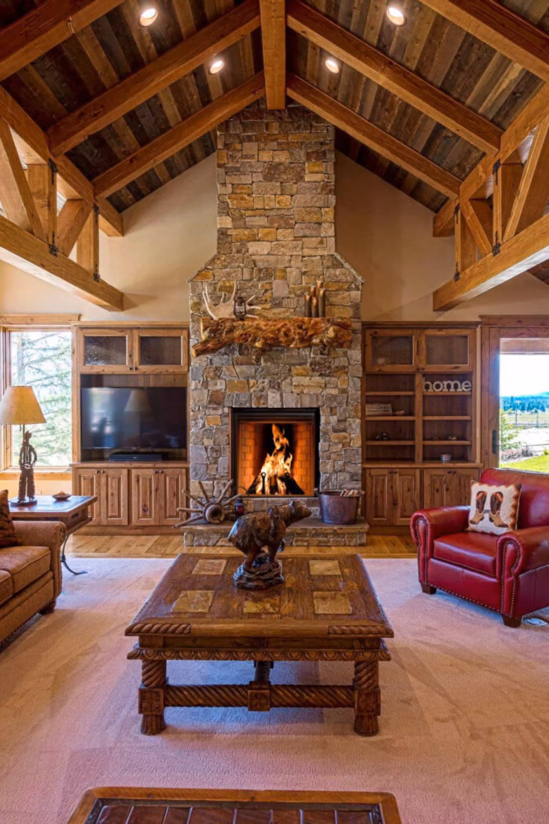 Grand stone chimney wood fireplace under timber trusses