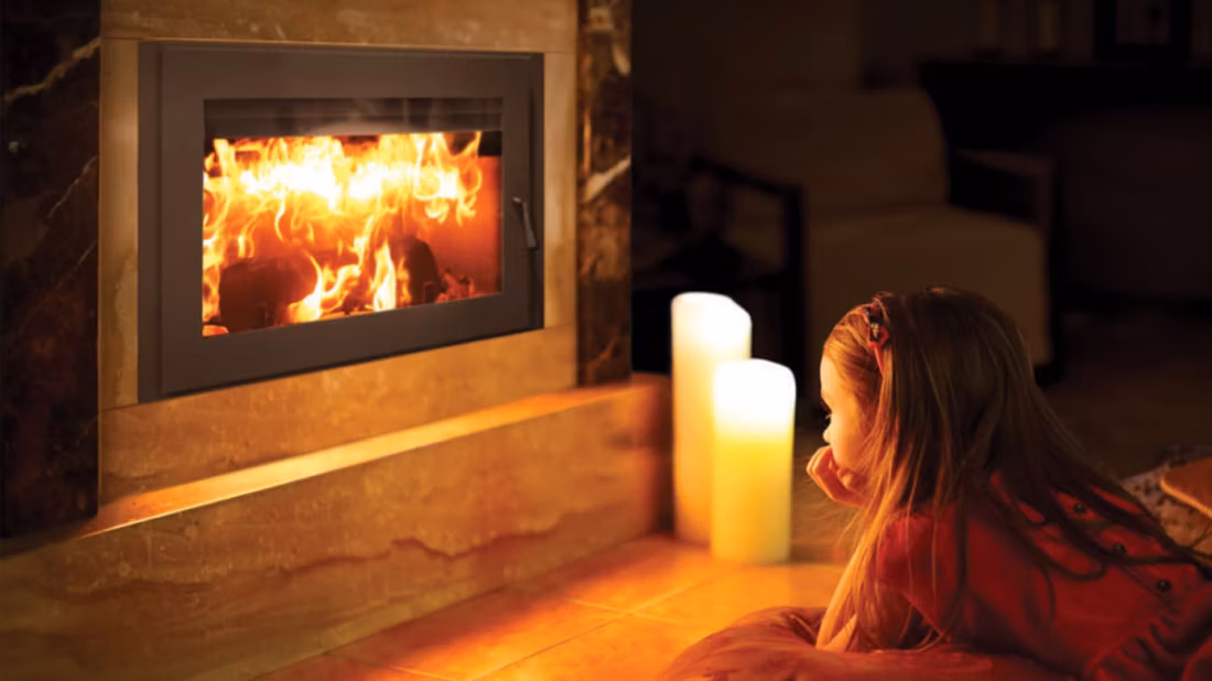 Young girl gazing at glowing wood fireplace insert